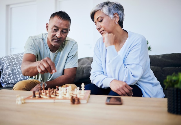 Partido de ajedrez de pareja mayor y hogar con estrategia de pensamiento y mentalidad para el poder cerebral relajarse y vincular Anciana hombre y sofá con ideas de juegos de mesa y lluvia de ideas para el desafío en casa