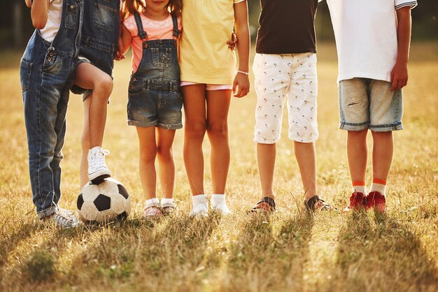 Partikelansicht sportlicher Kinder mit Fußball steht am sonnigen Tag zusammen auf dem Feld.