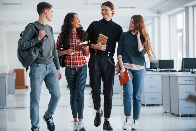 Partilhando informação. Grupo de jovens caminhando no escritório no intervalo