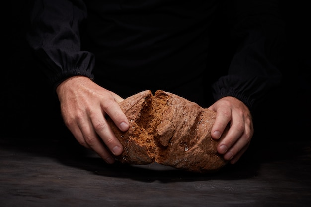 partir el pan conmigo Vista recortada del chef masculino rompiendo pan de masa fermentada recién horneado