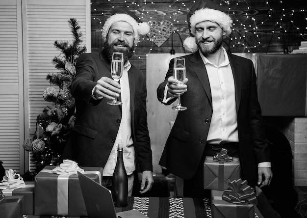 Party mit Champagner Geschäftsleute trinken Champagner auf der Party Kollegen feiern das neue Jahr Männer formelle Anzüge und Weihnachtsmützen halten Champagnergläser Cheers-Konzept Neujahrs-Firmenfeier