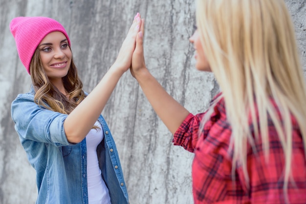 Party-Person-Leute im Teenageralter beste Trend-Stil-Wand gewinnen Swag-Zeichen-Spiel-Touch-Konzept. Nahaufnahme des Porträts einer charmanten, süßen, süßen hübschen Dame, die einem Freund einzeln auf grauem Hintergrund High Five gibt