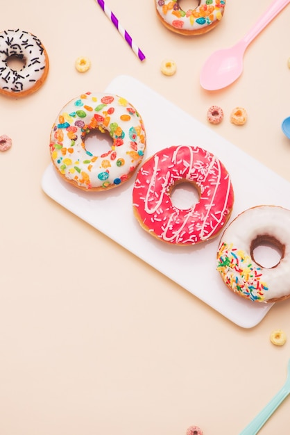 Party. Verschiedene bunte zuckerhaltige runde glasierte Donuts und Getränkeflaschen auf hellem Hintergrund.