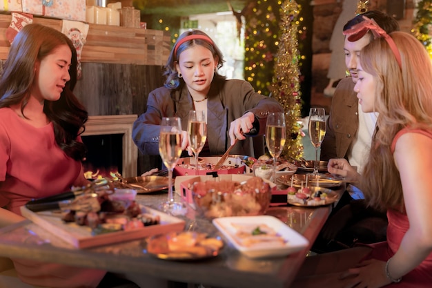 Party von schönen asiatischen Freundinnen und Männern, die eine Frau feiern, die Pizza auf dem Tisch serviert?