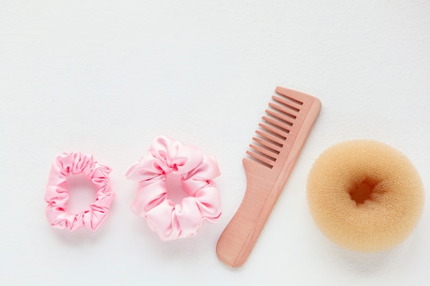 Foto pasador de cepillo de madera y scrunchy rosa de seda sobre blanco, herramientas de peluquería y accesorios para laicos planos