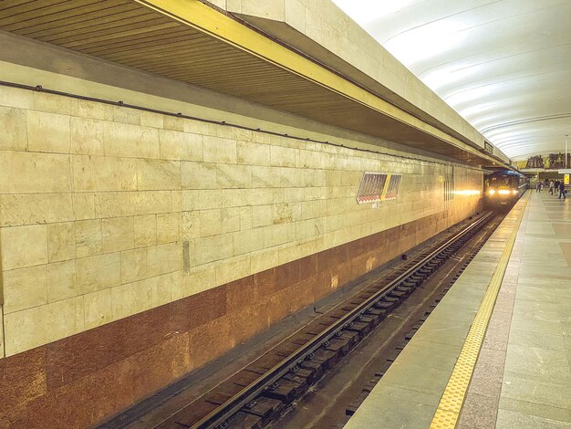 Pasaje subterráneo en el pasillo subterráneo del túnel subterráneo con trenes y rieles bajo electricidad