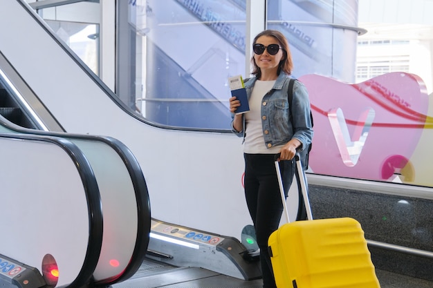 Pasajera en el interior de la terminal del aeropuerto con equipaje, maleta y mochila