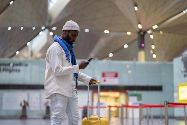 Pasajero afroamericano mirando la tarjeta de embarque móvil en el teléfono inteligente en el área de registro