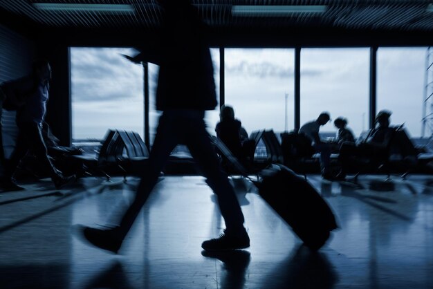 Pasajero con equipaje caminando a lo largo de una sala de salida vacía del aeropuerto