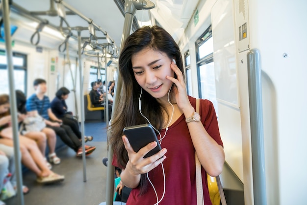 Pasajero de mujer asiática con traje casual usando y escuchando la canción