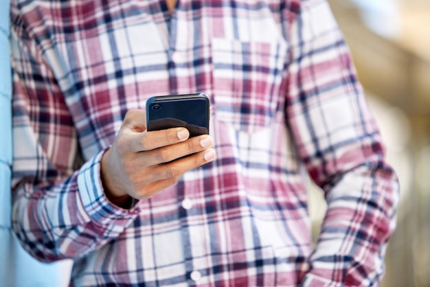 Pasando el rato durante su tiempo libre Primer plano de un estudiante irreconocible usando un teléfono celular en el campus