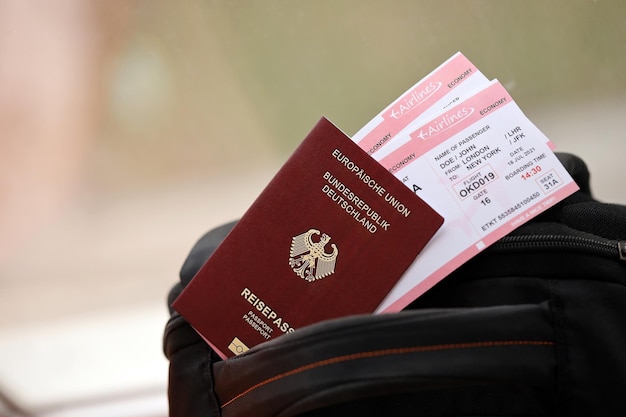 Pasaporte alemán rojo de la Unión Europea con billetes de avión en una mochila turística