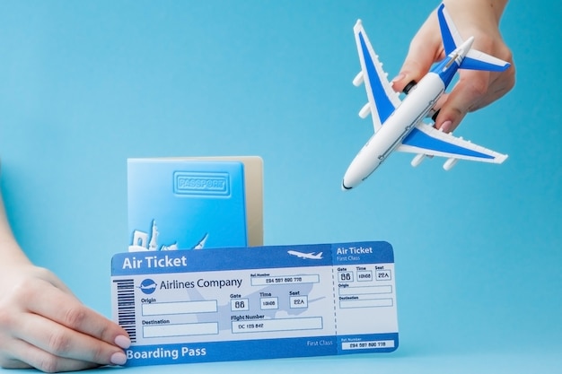 Pasaporte, avión y boleto aéreo en mano de mujer en azul