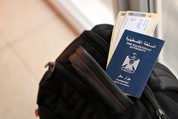 Pasaporte azul de la autoridad palestina con billetes de avión en una mochila turística de cerca