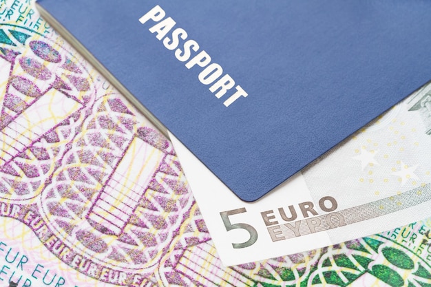 Pasaporte azul con billete de cinco euros en el fondo de la visa Schengen