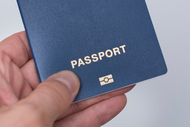 Pasaporte azul con biometría en la mano de un hombre.