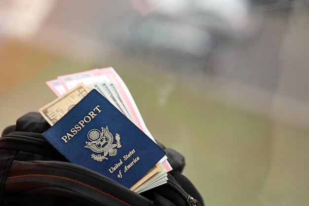 Pasaporte azul de los Estados Unidos de América con dinero y boletos de avión en una mochila turística