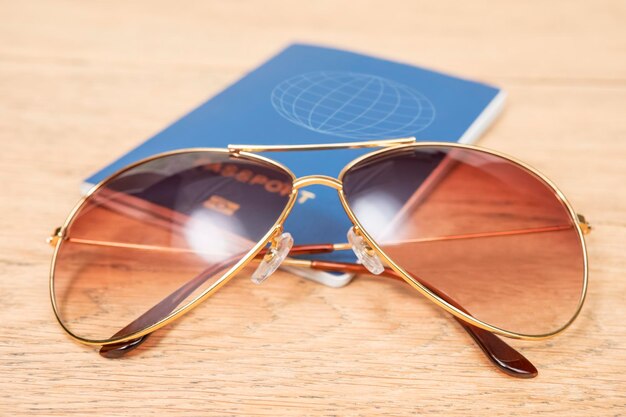 pasaporte azul y gafas de sol en una mesa de madera como concepto de viaje de vacaciones