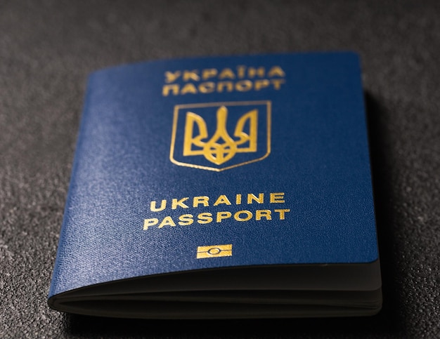 Pasaporte biométrico extranjero azul ucraniano con un chip en un fondo texturizado negro Ucrania