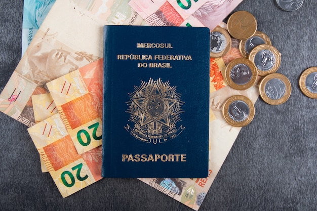 Pasaporte brasileño con billetes y monedas reales.