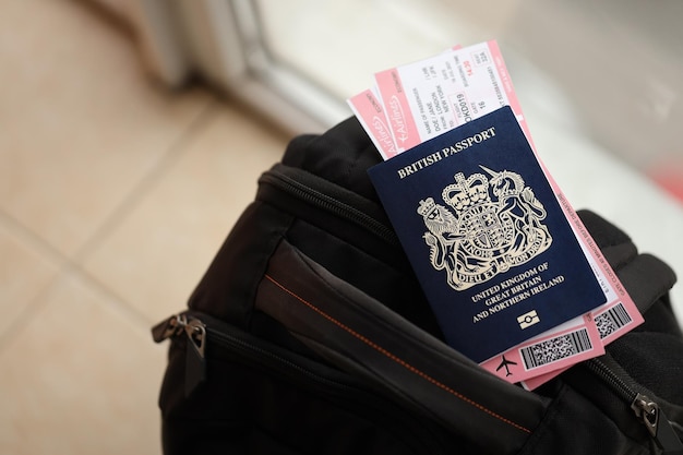 Pasaporte británico azul con billetes de avión en una mochila turística