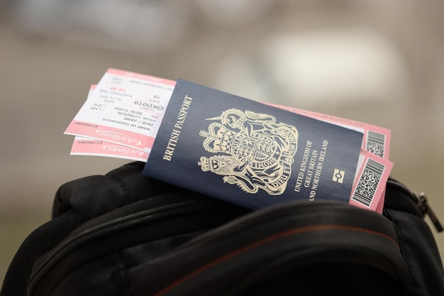 Pasaporte británico azul con billetes de avión en una mochila turística