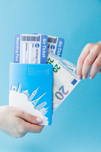 Pasaporte, euro y billete de avión en mano de mujer en azul