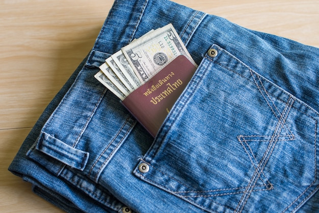 Pasaporte de Tailandia y dólar de plata en los jeans de bolsillo