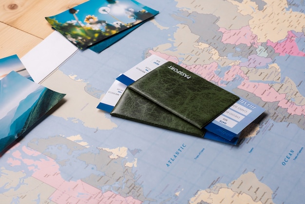 Foto pasaportes y boletos colocados en un mapa mundial de papel con fotos escénicas