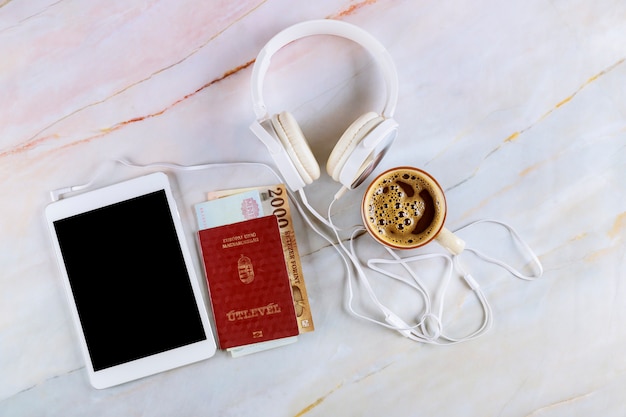 Los pasaportes de ciudadanía húngara, una taza de café exprés negro, tableta y auriculares.