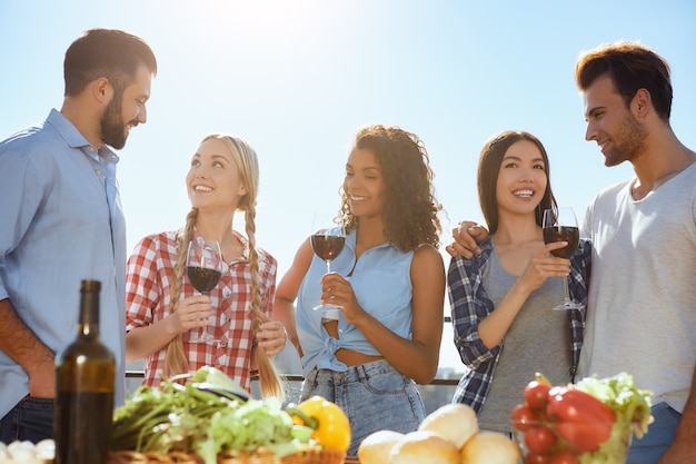 Pasar un buen rato con un grupo de amigos de gente joven y feliz sonriendo y bebiendo vino