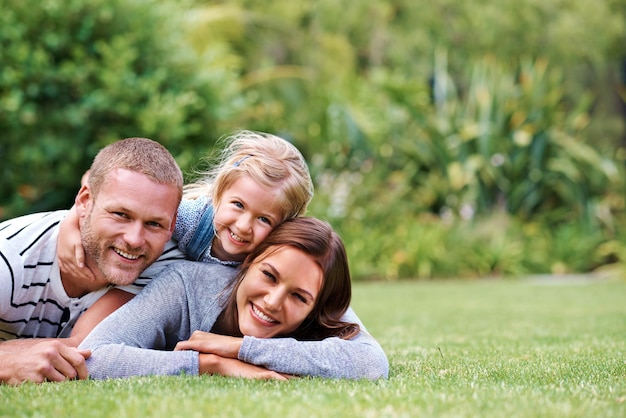 Pasar el mejor momento con mamá y papá Retrato de una familia feliz de tres tumbados afuera en el césped