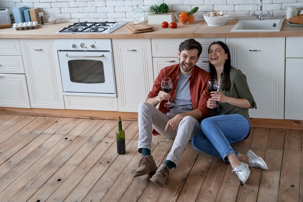 Foto pasar tiempo en casa joven pareja romántica feliz esposa y esposo sentados en el suelo en el