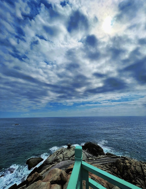 Una pasarela azul y verde está en las rocas junto al océano.