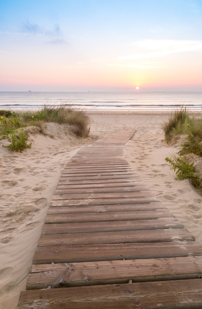 Pasarela de madera entrando a la playa al amanecer