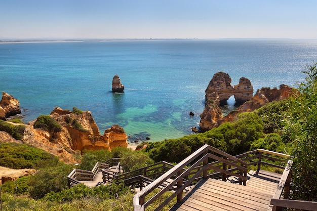 Foto pasarela de madera a la hermosa playa con acantilados en algarve, portugal