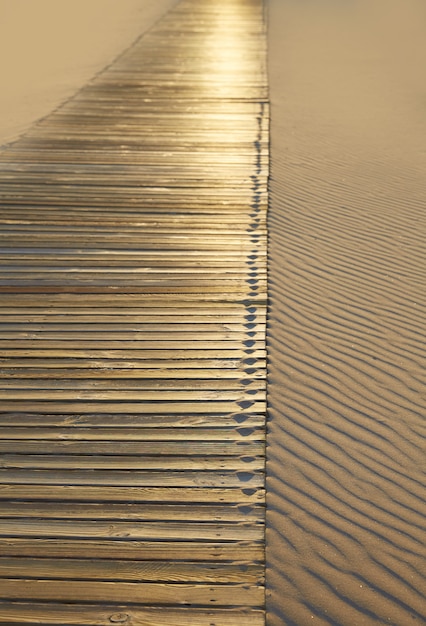 Pasarela de madera de playa y textura de dunas de arena.