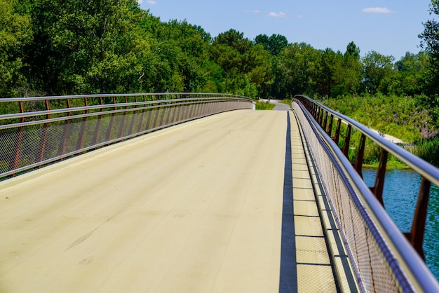 Pasarela de puente de acero de cruce vacía con barandilla de aluminio sobre el río para peatones