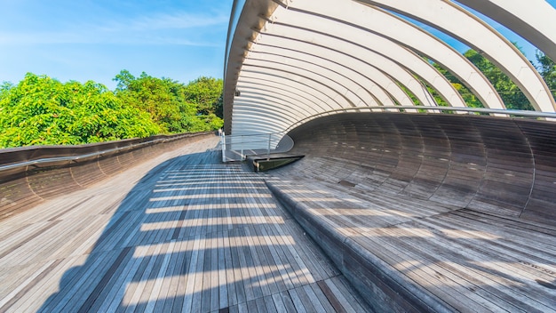 Pasarela de puente de madera con sombra de estructura de acero de la luz del sol con el árbol de árbol verde