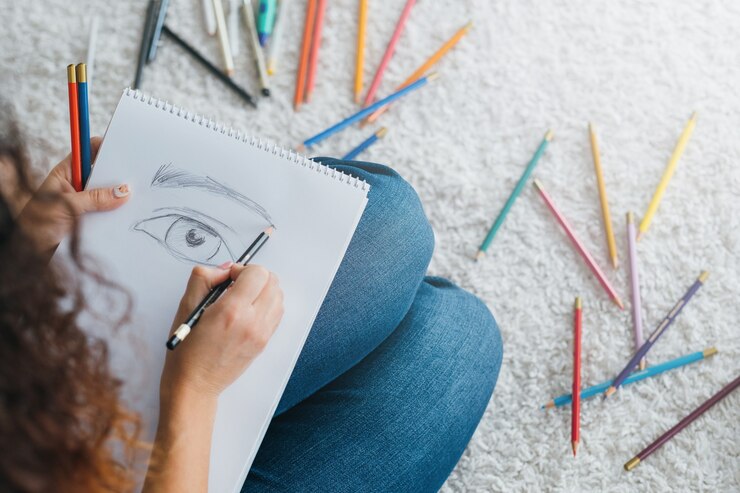 Foto pasatiempo de bellas artes. artista femenina sentada relajada en el suelo con muestras de colores de pintura y lápices