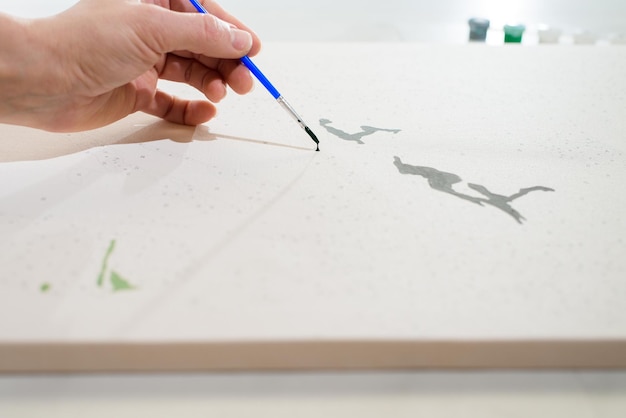 Pasatiempo en casa pintando por números para dibujar desde arriba una vista de manos de mujeres sosteniendo un pincel con pinturas.