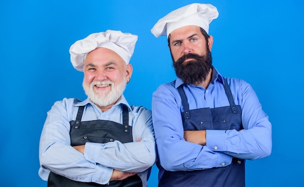 Pasatiempo culinario padre e hijo. Hombres barbudos maduros cocineros profesionales de restaurante. Los hombres chef usan delantales. Restaurante familiar. Trabajadores del café. Cocina de restaurante. Industria culinaria. Personal del restaurante.