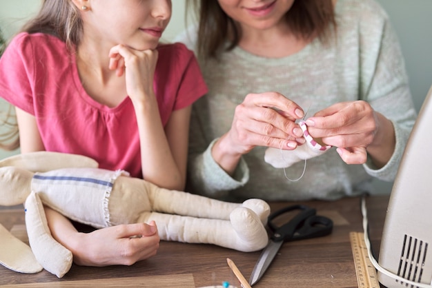 Pasatiempo familiar creativo hecho a mano y ocio, madre e hija juntas cosen muñeca de juguete de conejito. Mujer enseña habilidades de costura de niña, hablando