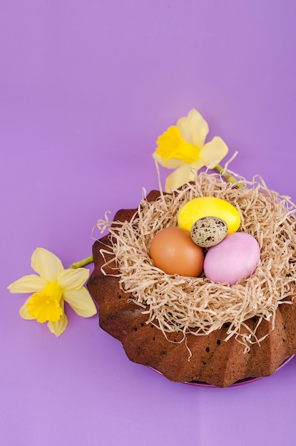 Páscoa ainda vida, bolo de Páscoa, frango e ovos de codorna, sobre um fundo violeta.