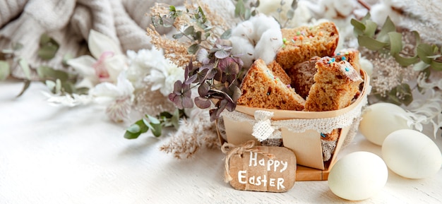 Páscoa ainda vida com pedaços de bolinho festivo, ovos e flores sobre um fundo claro desfocado. Conceito de férias da Páscoa.