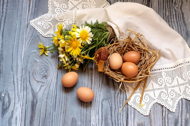 Páscoa ainda vida Velas de margaridas amarelas e ovos em uma mesa de madeira fechada