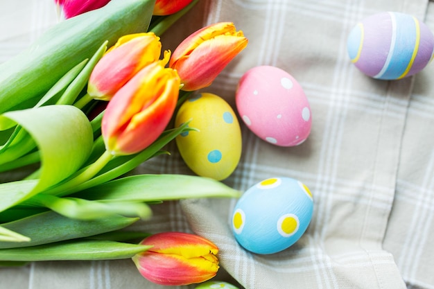 páscoa, feriados, tradição e conceito de objeto - close-up de ovos de páscoa coloridos na cesta e flores de tulipa