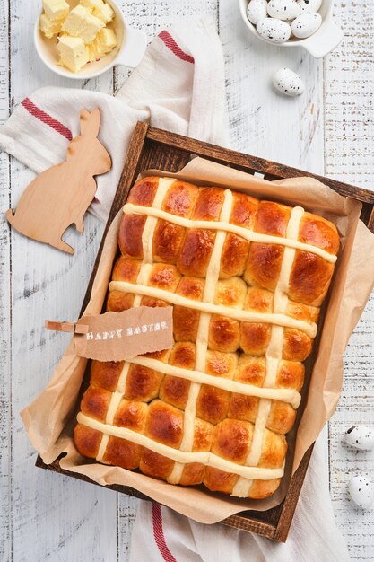 Páscoa Hot Cross Buns. Café da manhã tradicional e decorações do feriado de cozimento da Páscoa rabbiton fundo branco de madeira. Cores brilhantes, vista de cima, na mesa de madeira.