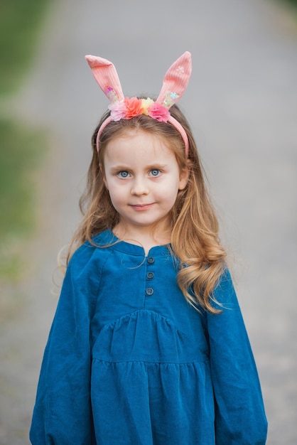 Páscoa Menina bonita com cabelo longo encaracolado com orelhas de coelho em flores de cerejeira Férias de primavera