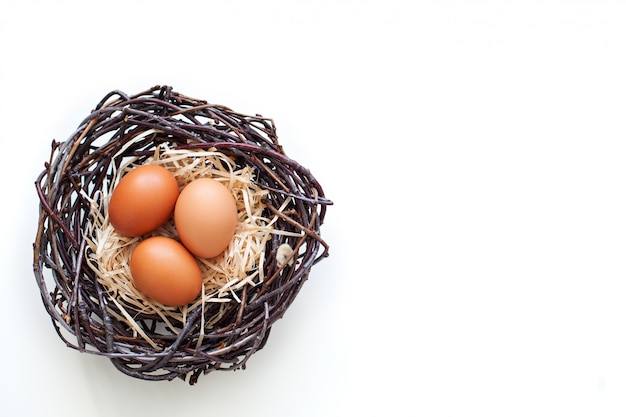 Páscoa! Ovos de galinha em um ninho com galhos, agricultura. Ovos de Páscoa em cima da mesa no ninho. Ovos de Páscoa bege. Ovos em um fundo branco. Fazenda. Comida de ninho de frango. Alimentação saudável.